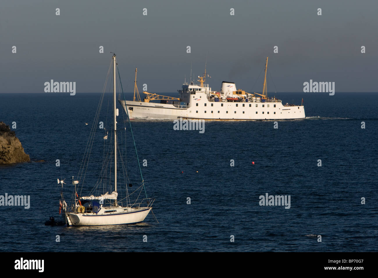 Le traversier de passagers 111 Scillonian passe un yacht amarré sur la façon de les Îles Scilly à Penzance, Cornwall. Banque D'Images