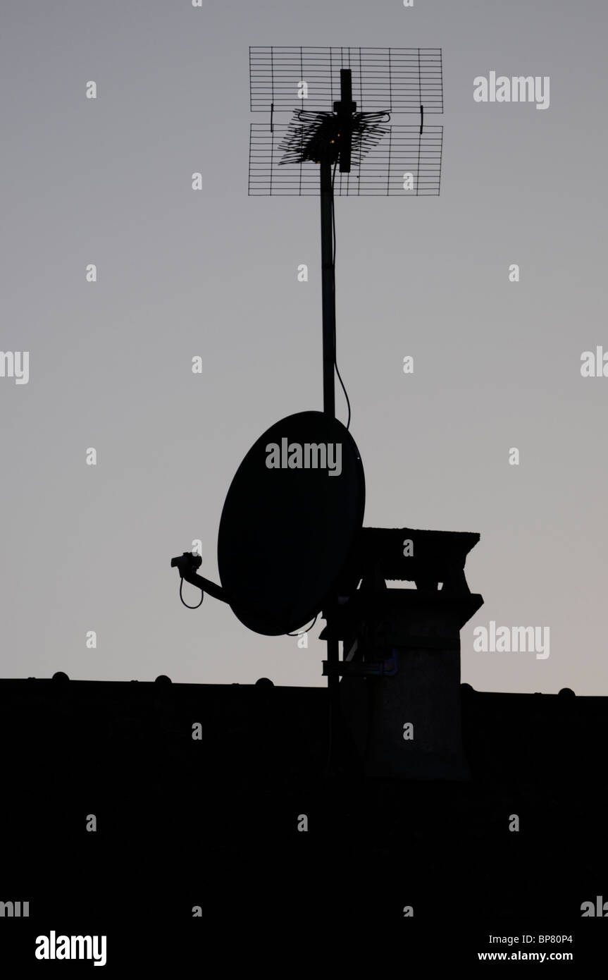 La silhouette d'antenne satellite et Sky s'antenne terrestre monté sur une maison. Banque D'Images