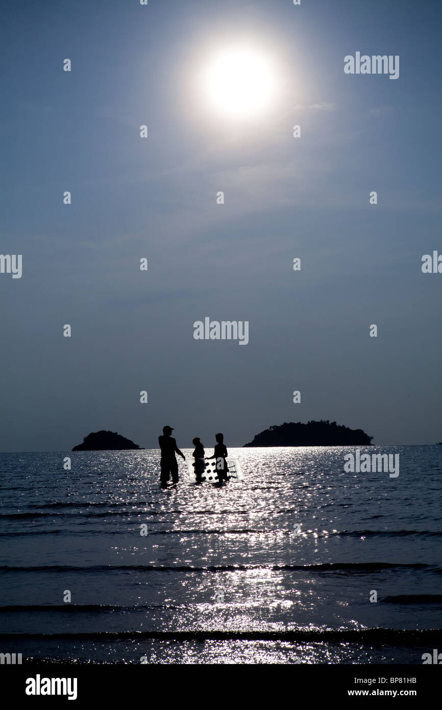 Position de la famille dans la mer et soleil avec un lilo, Koh Chang, Thaïlande. Banque D'Images