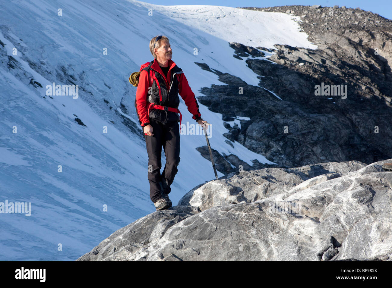 Mountaineer avec piolet, debout sur un rocher, Clariden, Canton d'Uri, Suisse Banque D'Images