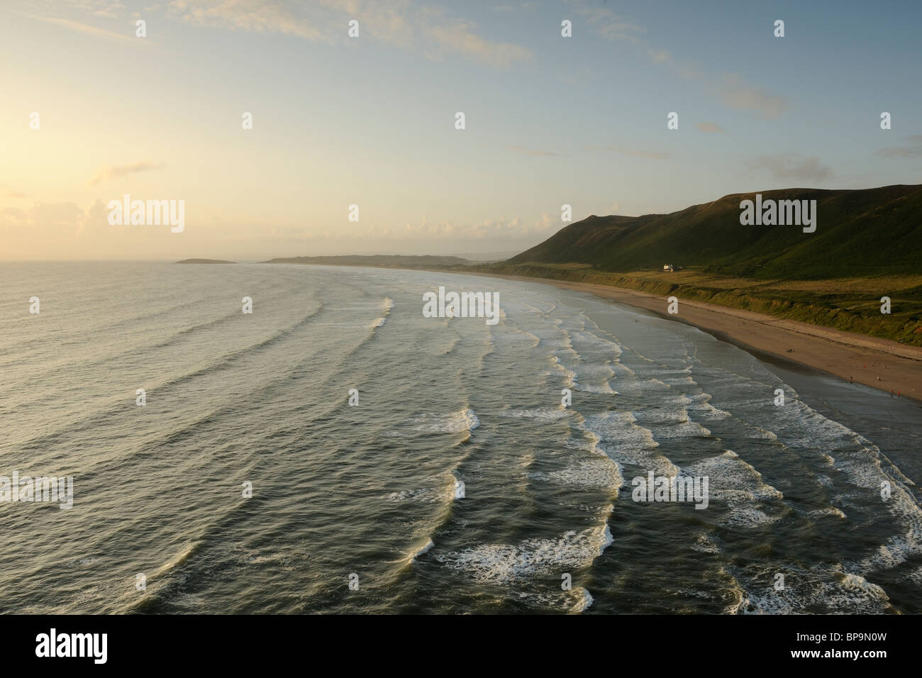Des vagues en de Rhossili beach au coucher du soleil. Rhossili est sur la péninsule de Gower, près de Swansea, Pays de Galles du Sud. Banque D'Images