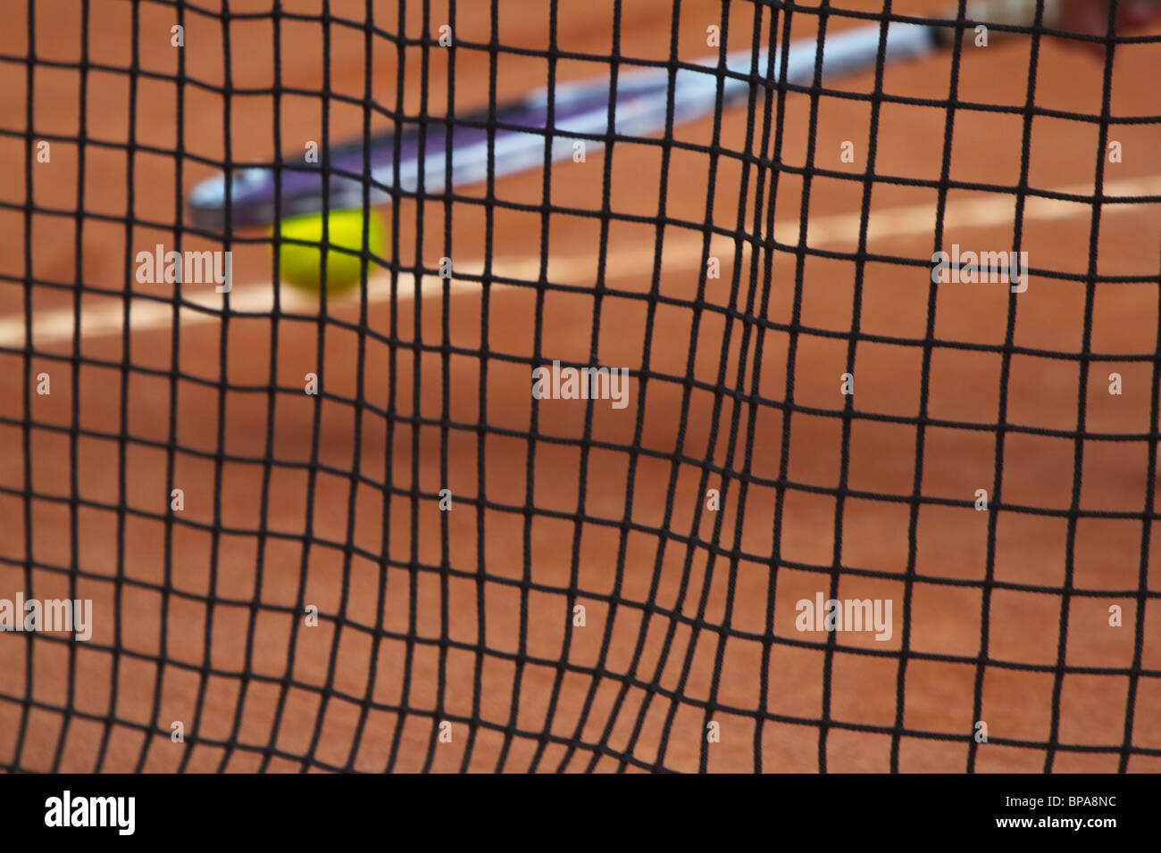 Terre Battue. Regardant à travers le net, raquette de tennis la balle qui rebondit. Selective focus dof 's'. L'horizontale Banque D'Images