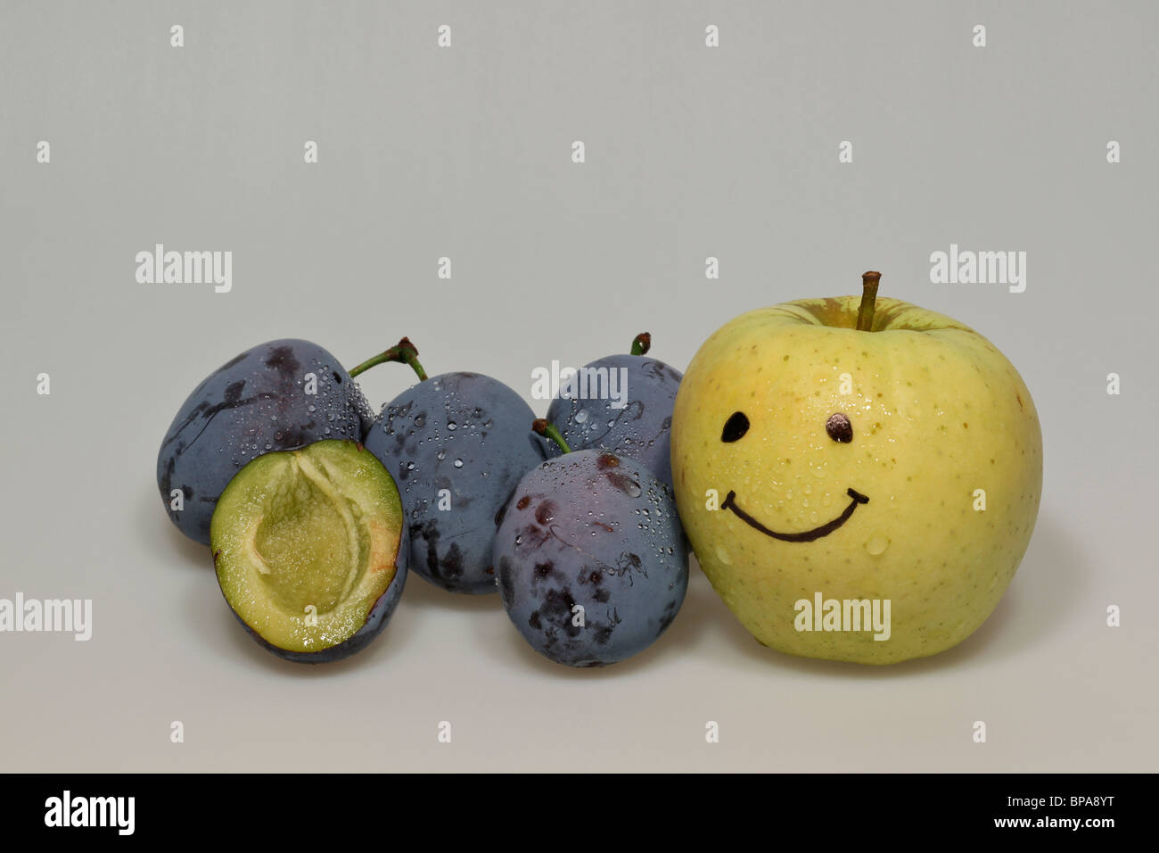 Les prunes bleu avec des gouttes d'eau et de smiley yellow apple Banque D'Images