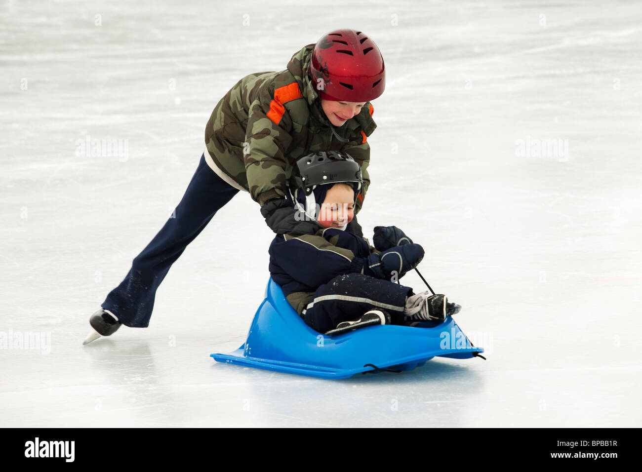 Edmonton, Alberta, Canada, et un homme poussant un jeune garçon dans un traîneau sur une patinoire en plein air Banque D'Images