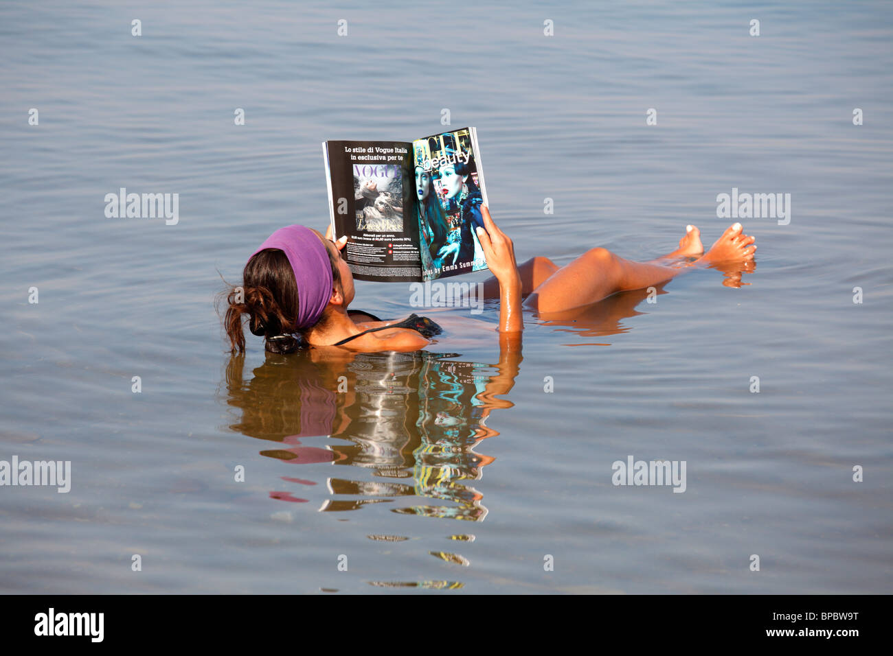 Jeune femme flottant et la lecture d'un magazine dans la mer Morte, Jordanie Banque D'Images