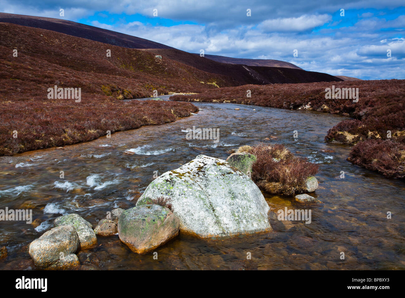 L'Écosse, les Highlands écossais, le Parc National de Cairngorms. Rivière qui traverse les collines de bruyère Gleann Eanaich. Banque D'Images