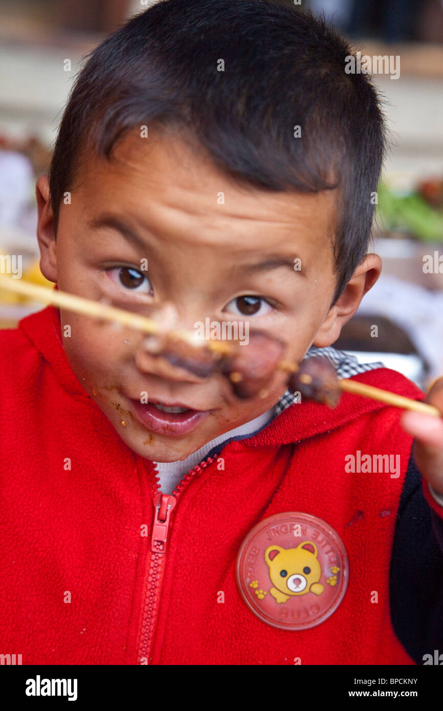 Boy eating street food à Shangri-La Zhongdian ou dans la province du Yunnan, Chine Banque D'Images