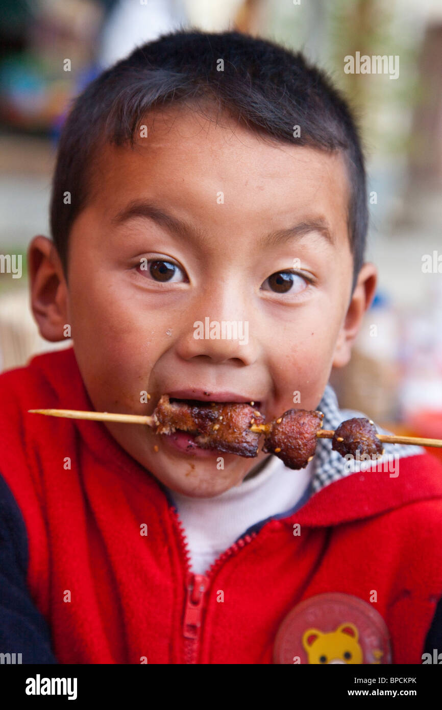 Boy eating street food à Shangri-La Zhongdian ou dans la province du Yunnan, Chine Banque D'Images