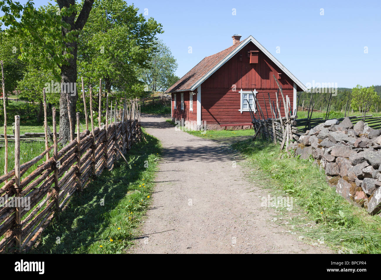 Route de gravier à côté de pays paysages avec une grange et une barrière en bois. Banque D'Images