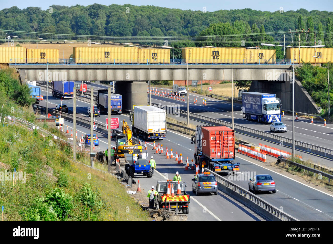 La route d'autoroute M 25 travaille cônes conteneur train de fret sur pont et camion options pour la logistique de transport de chaîne d'approvisionnement britannique Brentwood Essex Angleterre Banque D'Images