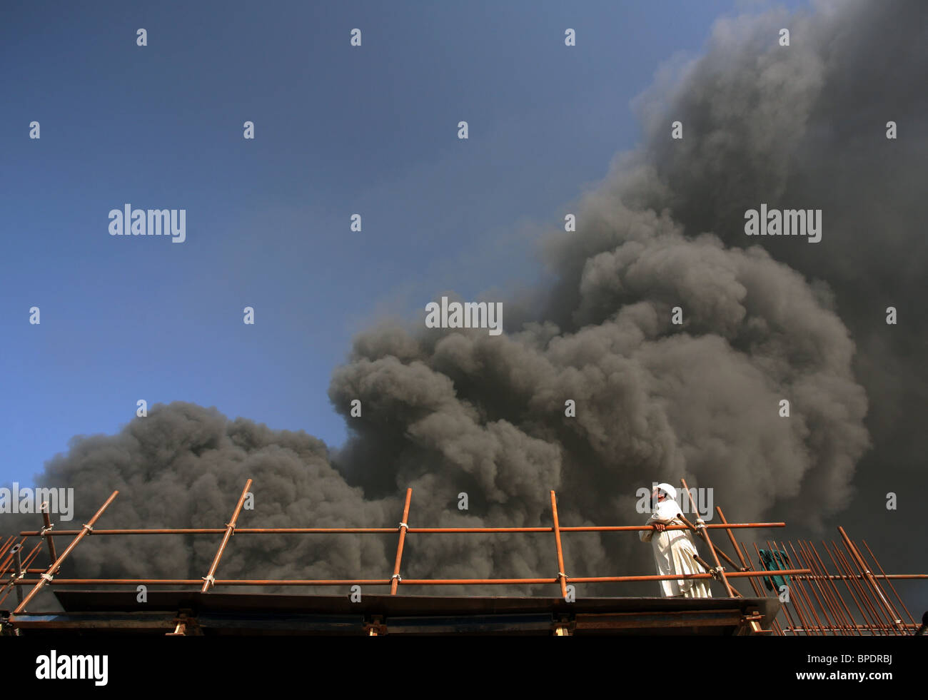 Un travailleur de la construction sur un échafaudage à à un sombre nuage de fumée, Dubai, Émirats Arabes Unis Banque D'Images