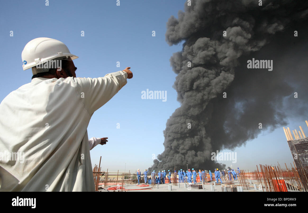 Un travailleur de la construction pointant sur un nuage noir de fumée, Dubai, Émirats Arabes Unis Banque D'Images