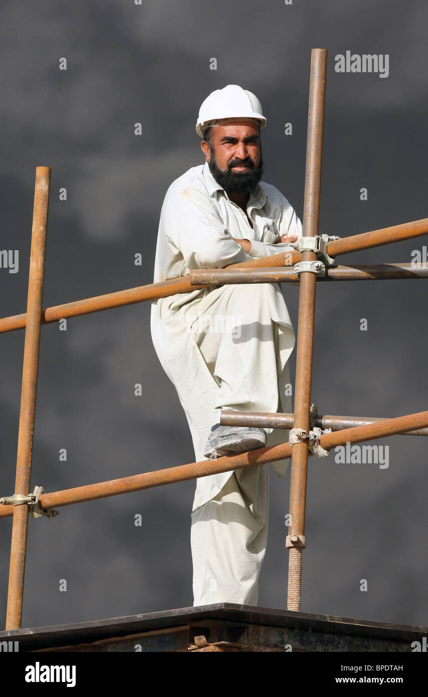 Un travailleur de la construction sur un échafaudage en face d'un sombre nuage de fumée, Dubaï, Émirats Arabes Unis Banque D'Images