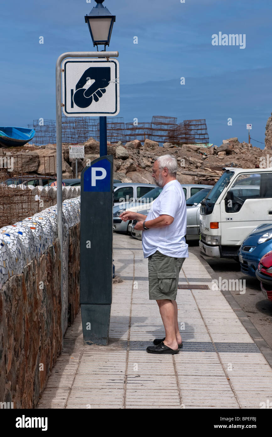 L'homme mettant l'argent dans un parking Gare paye (parking meter) à Puerto de Mogan, Grande Canarie Banque D'Images