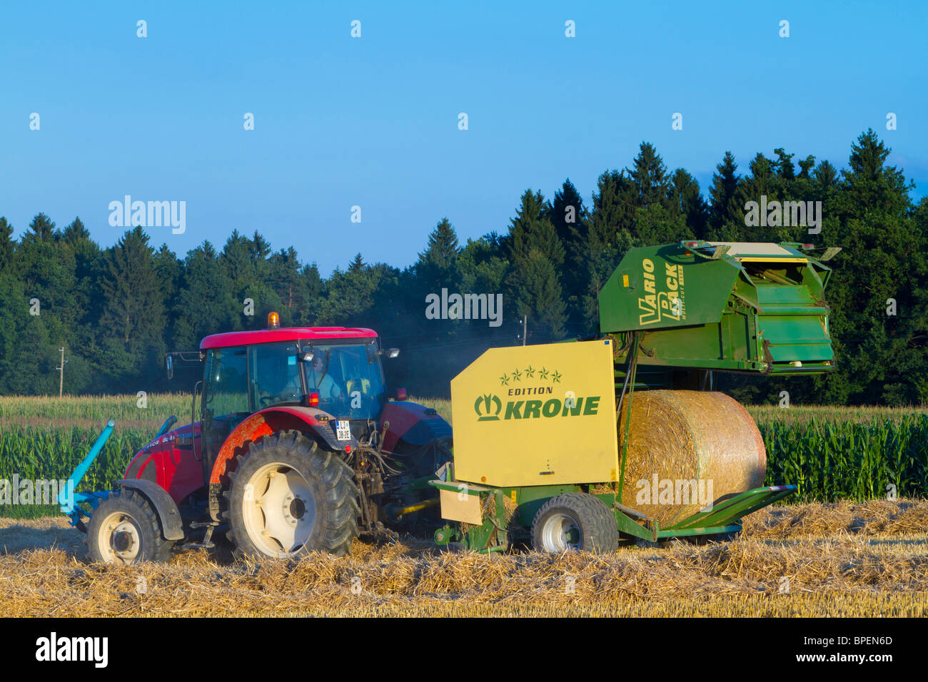 Un ouvrier dégage une balle de foin d'un Krone Vario Pack hay ramasseuse-presse. Banque D'Images