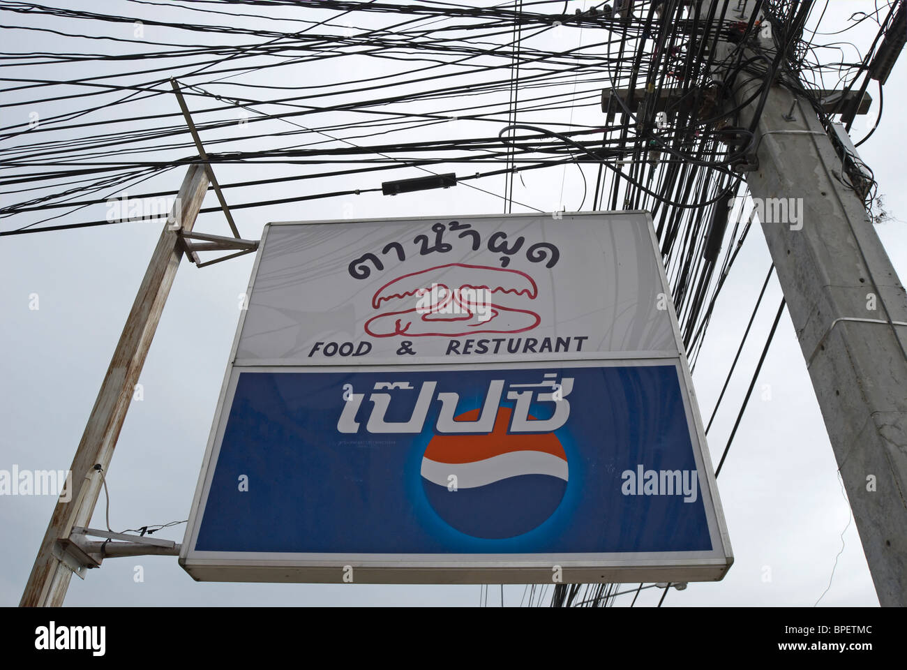 La langue thaï signe pour un restaurant appelé la trombe, à phetchabun, Thaïlande, Asie du sud-est, au-dessus d'une publicité pepsi Banque D'Images