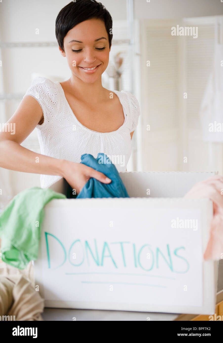 Mixed Race woman putting habillement en donation box Banque D'Images