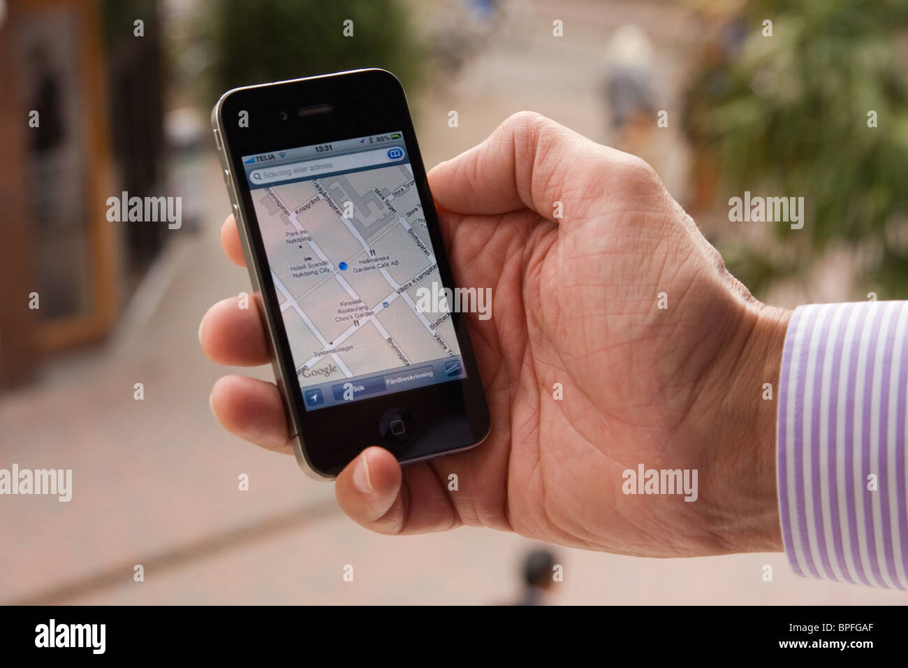 L'iPhone 4 dans la main d'un homme montrant l'application Google maps, soulignant son emplacement à Nyköping, Suède. Banque D'Images