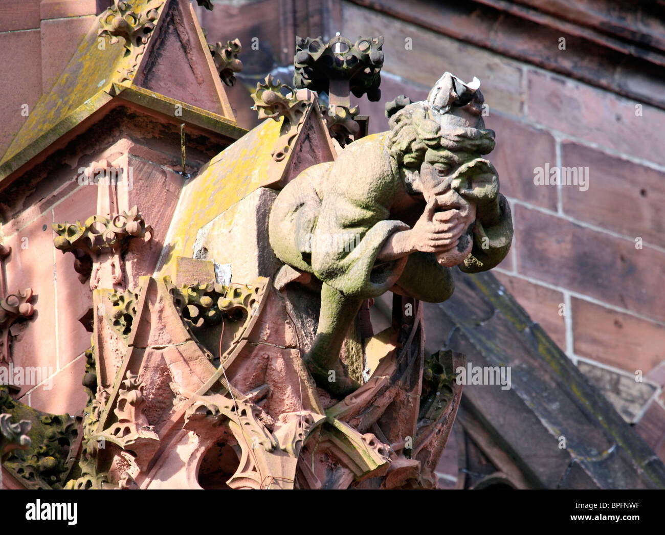 Gargoyle sous la forme d'un homme assis tenant son nez, à Freiburg, Freiburg im Breisgau, Baden Wurtemberg, Allemagne Banque D'Images