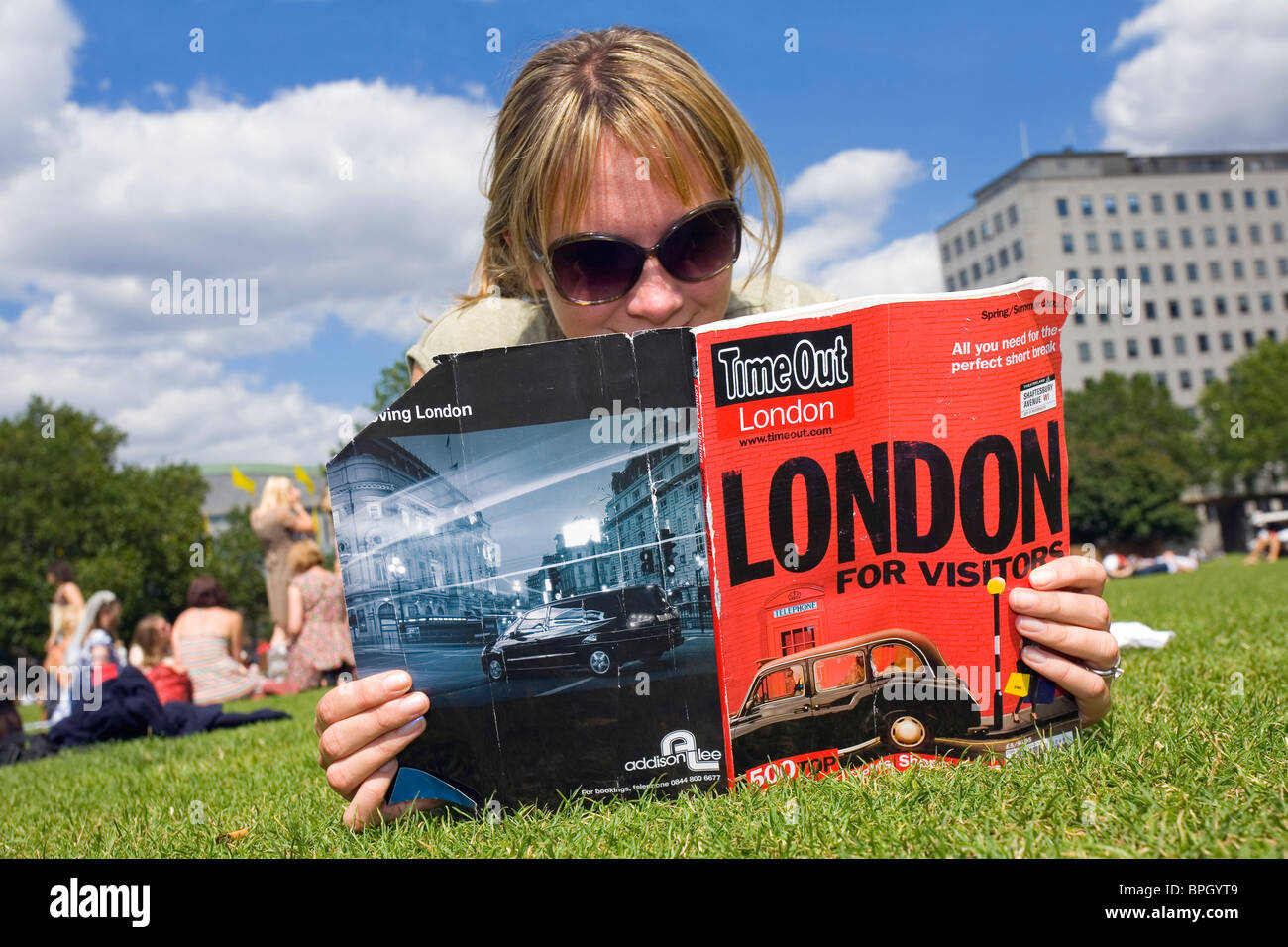 Femme lisant un magazine sur la pelouse, sur la rive sud de Londres Banque D'Images