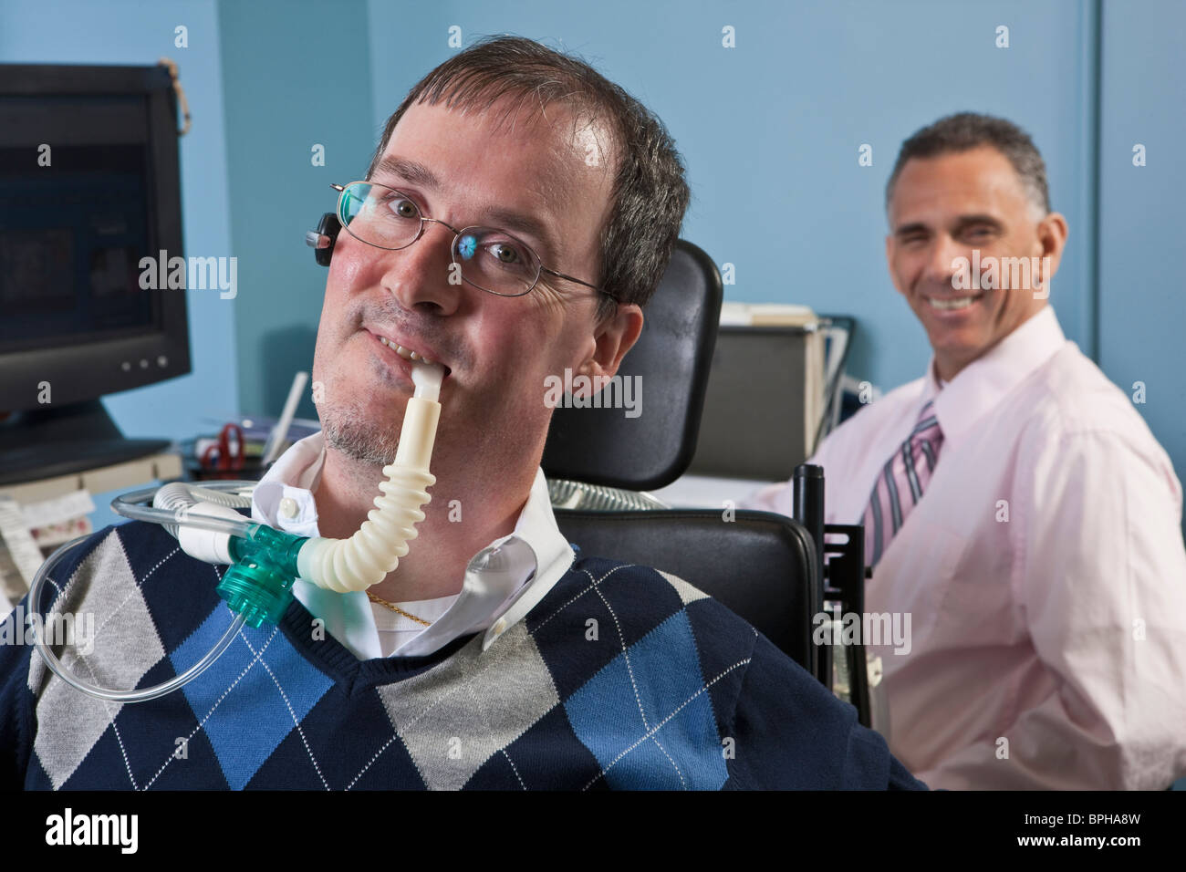Businessman with duchenne muscular dystrophy la respiration à l'aide d'un ventilateur et son collègue d'une atteinte de la moelle épinière derrière lui Banque D'Images