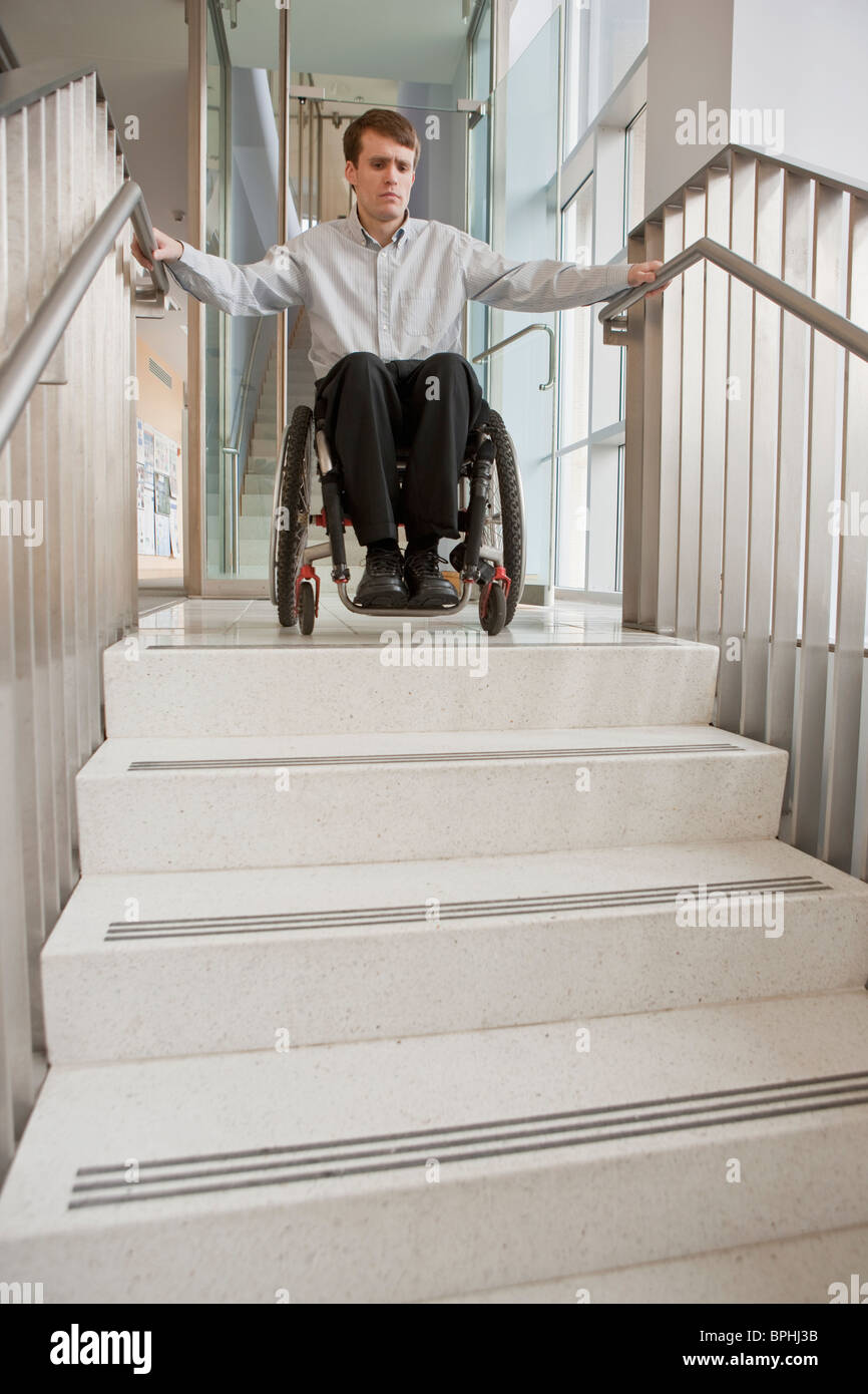 Businessman avec de la moelle épinière dans un fauteuil roulant en haut de l'escalier Banque D'Images