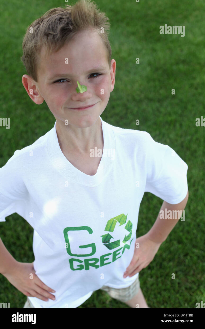 Smiling Young boy standing & portant avec 'go green 'tee shirt Banque D'Images