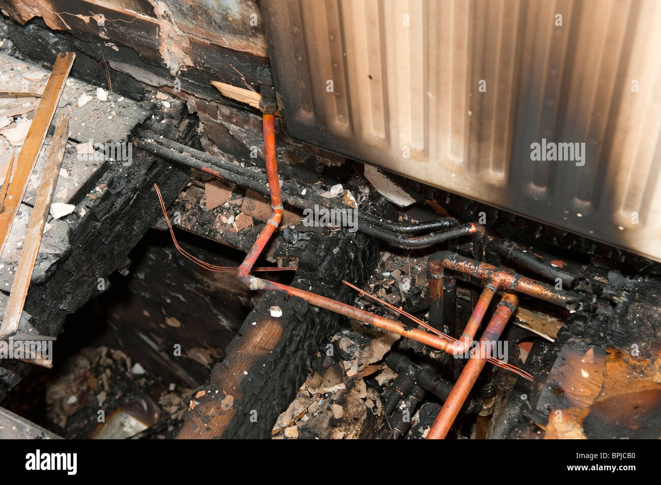 Solives brûlées et tube en cuivre à l'incendie Banque D'Images
