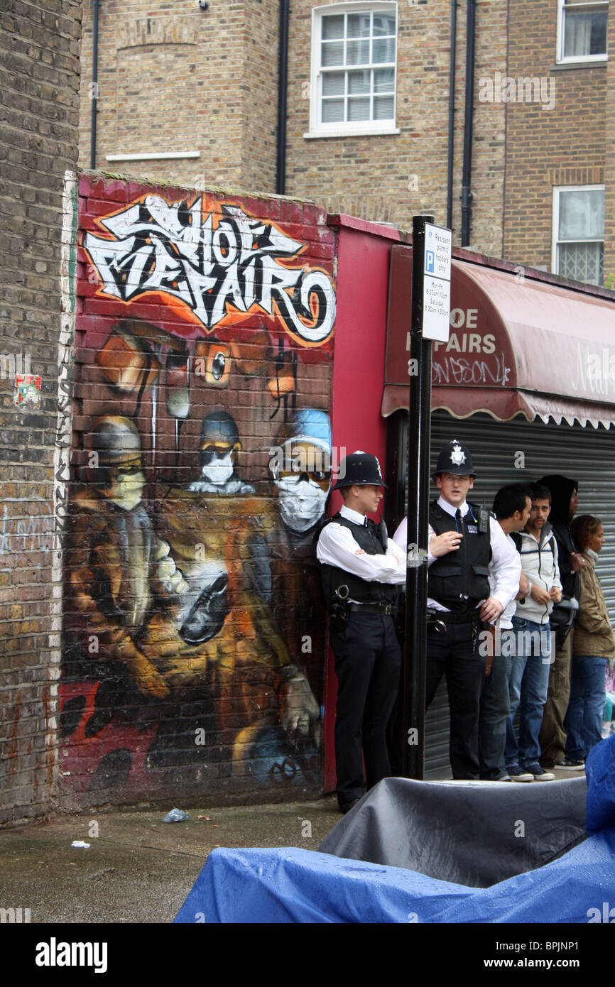 Deux hommes de police debout à côté de l'écriture graffiti au carnaval de Notting Hill London 2010 Banque D'Images