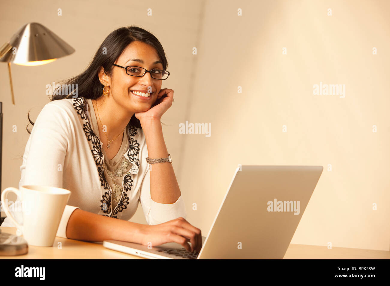 Mixed Race woman typing on laptop Banque D'Images