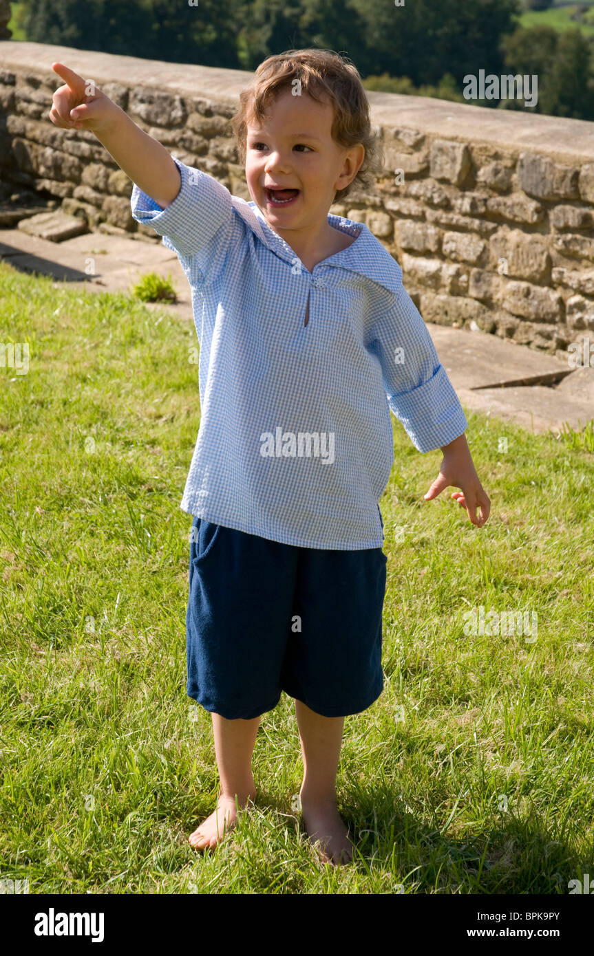 Petit garçon portant une chemise bleu et de pointage permanent Banque D'Images