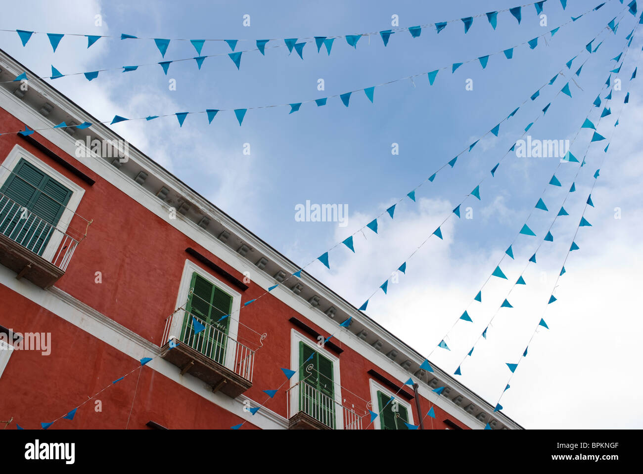 Maison rouge aux volets verts avec des drapeaux bleus en Italie Banque D'Images