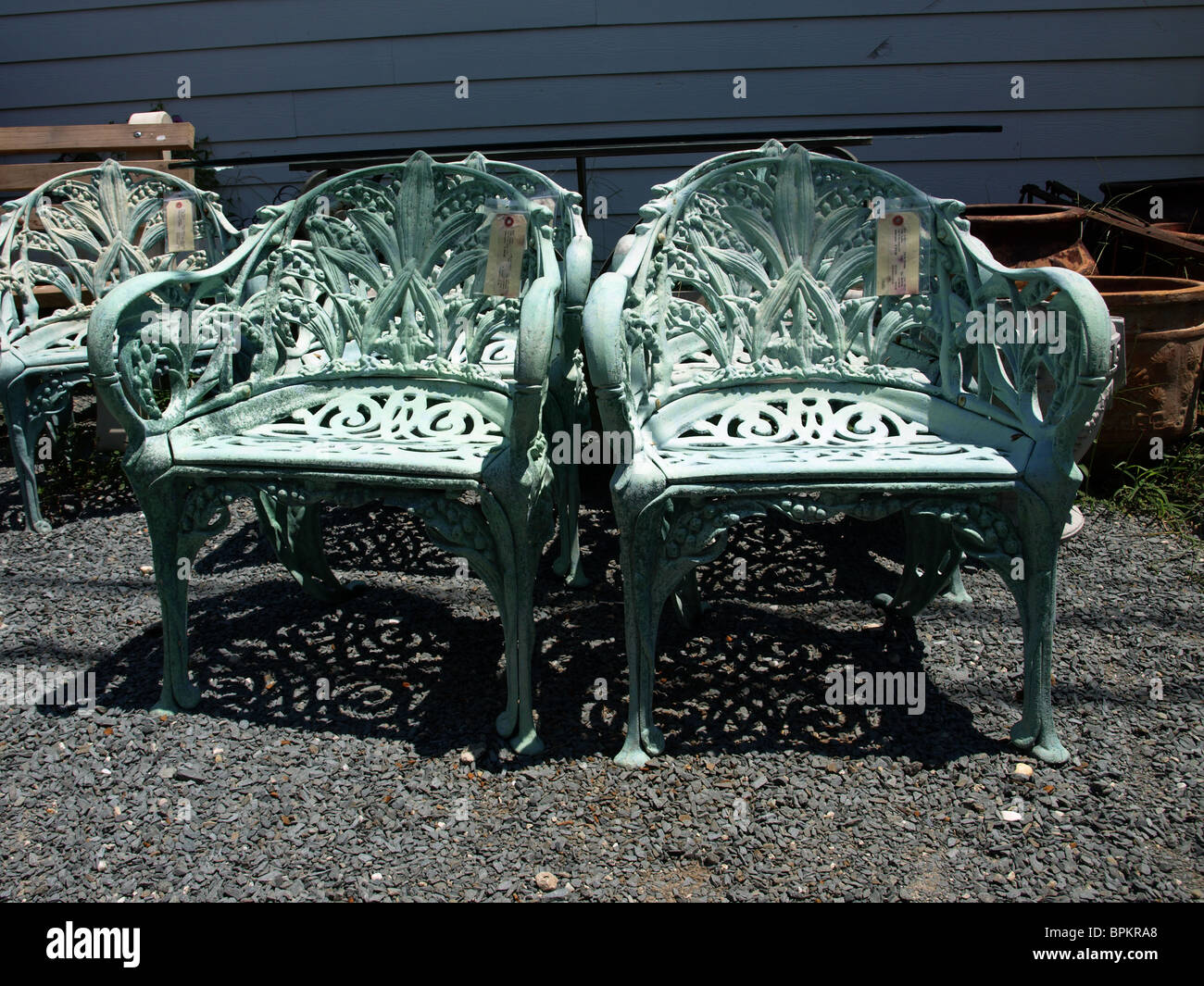Jardin en métal chaises d'extérieur de cour dans des motifs très cuivre avec ombres sur sol Banque D'Images