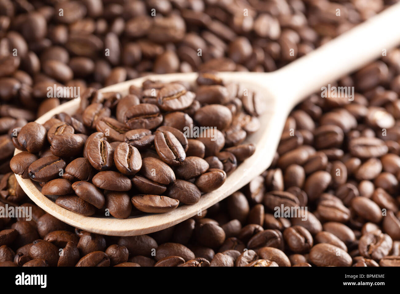 Les grains de café sur cuillère en bois Banque D'Images