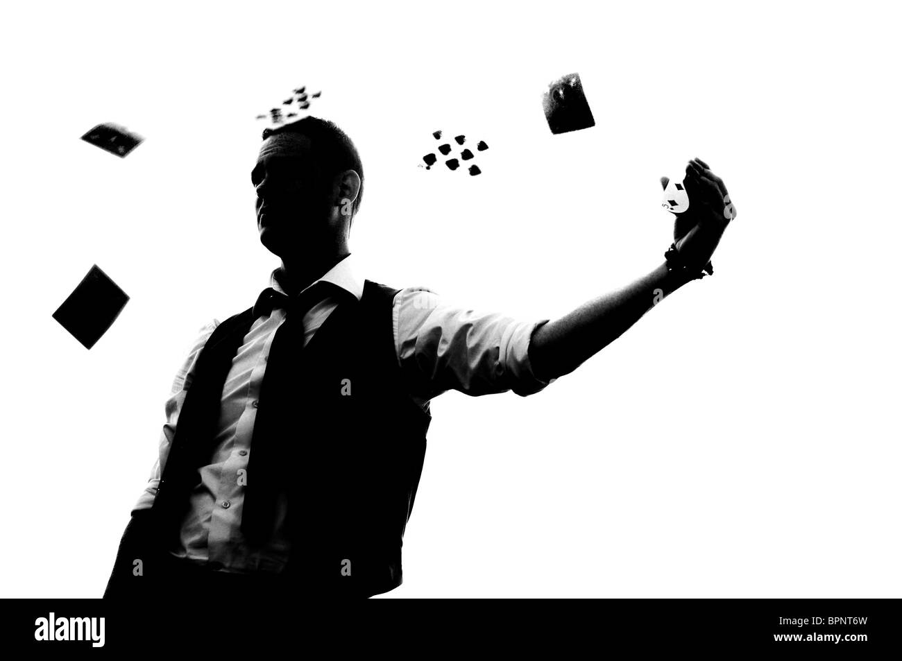 Le noir et blanc Silhouette de jeune magicien jeter jeux de cartes chez lui-même Banque D'Images