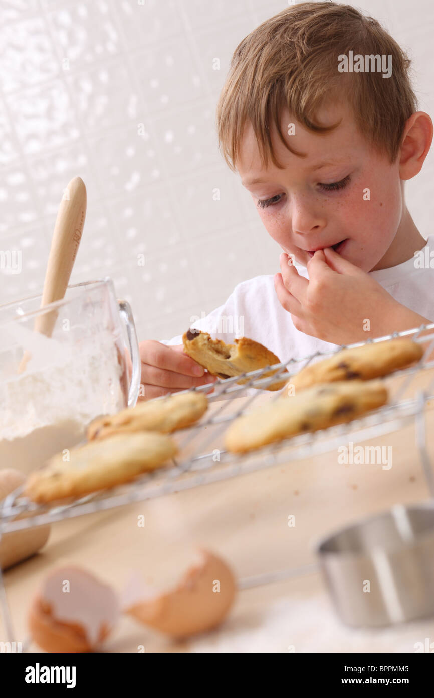 Jeune garçon dans la cuisine manger cookie Banque D'Images