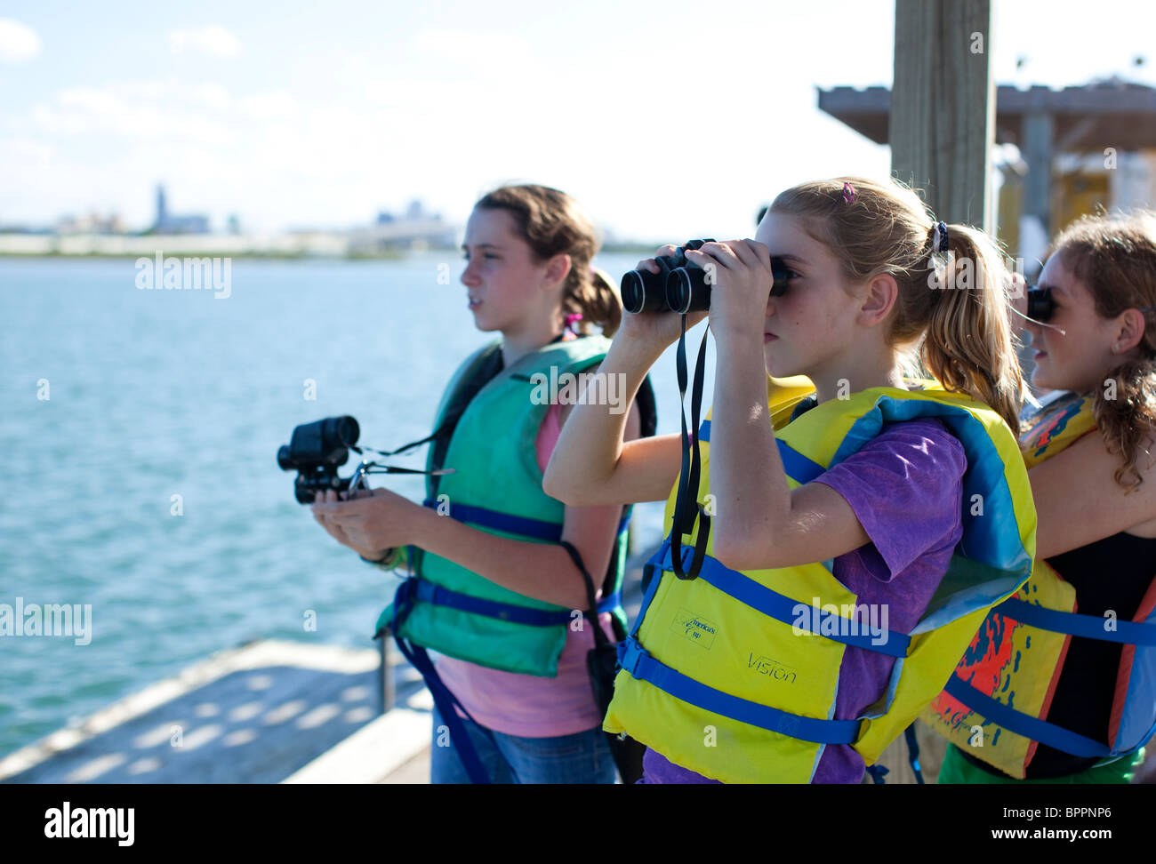 Les étudiants du secondaire utilisez des jumelles pour regarder les oiseaux de rivage dans la baie de Corpus Christi au cours de biologie marine excursion de classe Banque D'Images
