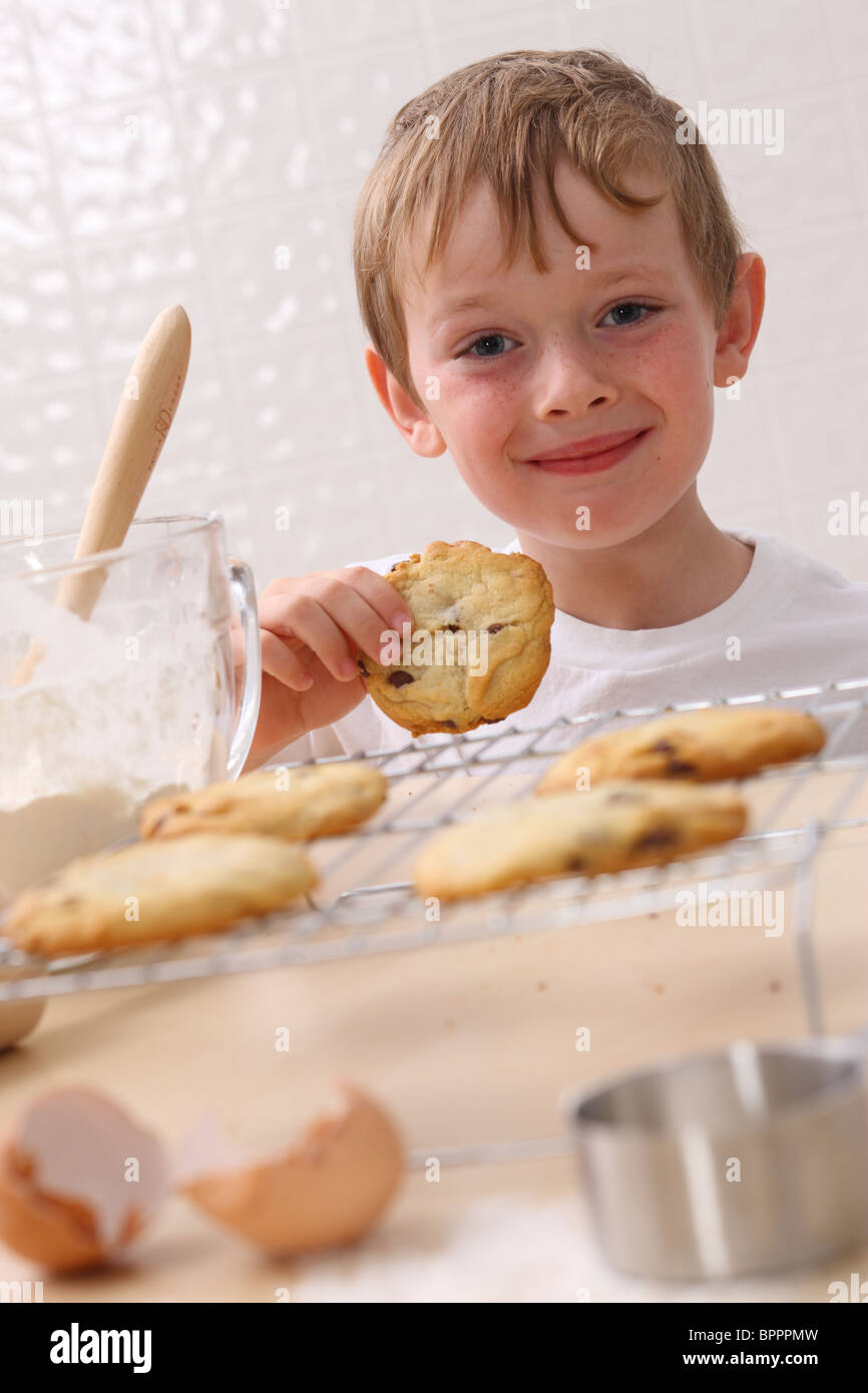 Jeune garçon dans la cuisine manger cookie Banque D'Images