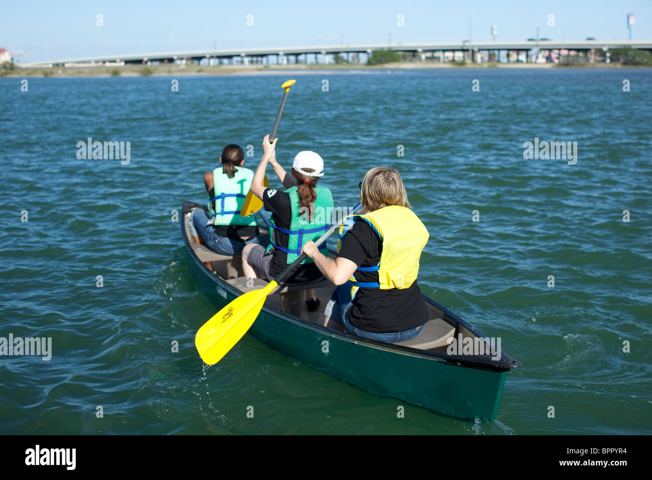 Les filles de l'école intermédiaire portant des gilets de pagayer leur canot dans la baie de Corpus Christi au cours de biologie marine excursion de classe Banque D'Images