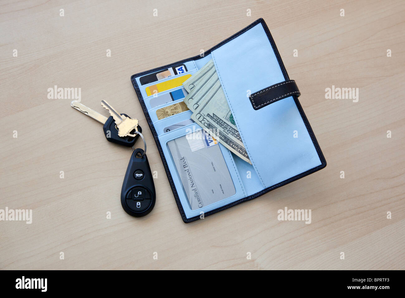 Porte-monnaie avec de l'argent et les cartes et clés de voiture sur la table Banque D'Images