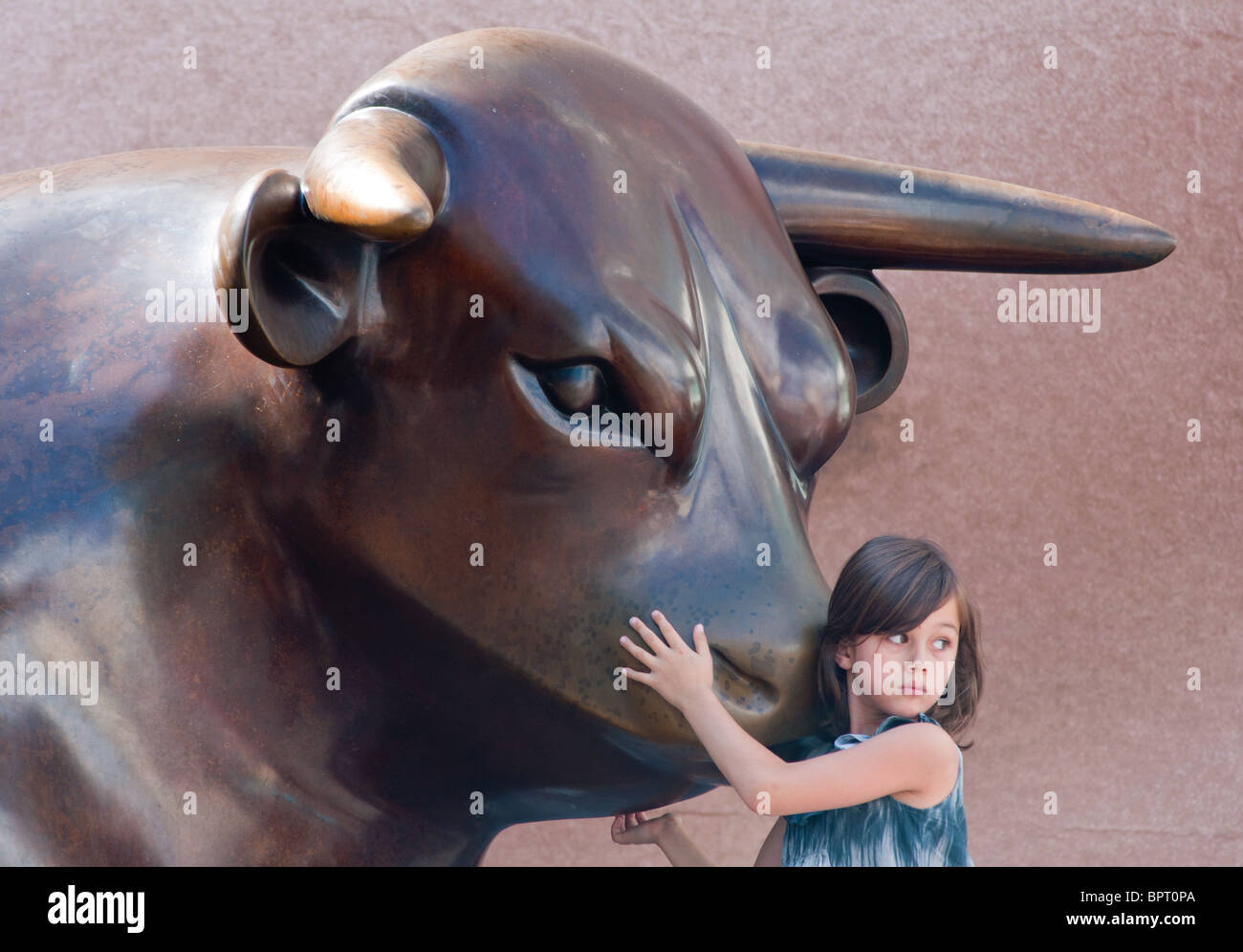 Petite fille avec le 'Bull' à l'extérieur de la sculpture centre commercial Bullring à Birmingham en Angleterre. Banque D'Images