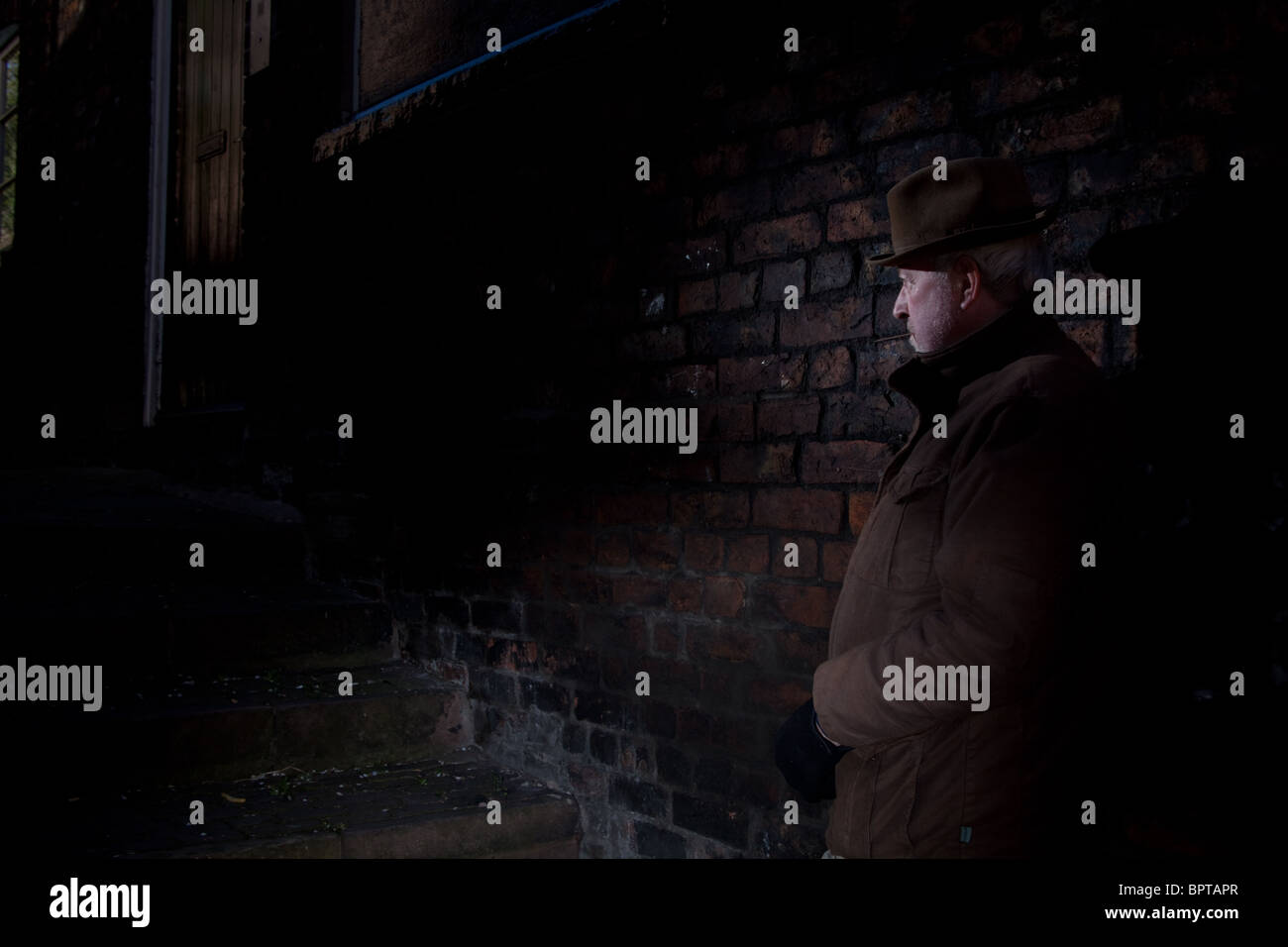 Film Noir représentant un homme dangereux et calme en attente dans une ruelle sombre. Banque D'Images