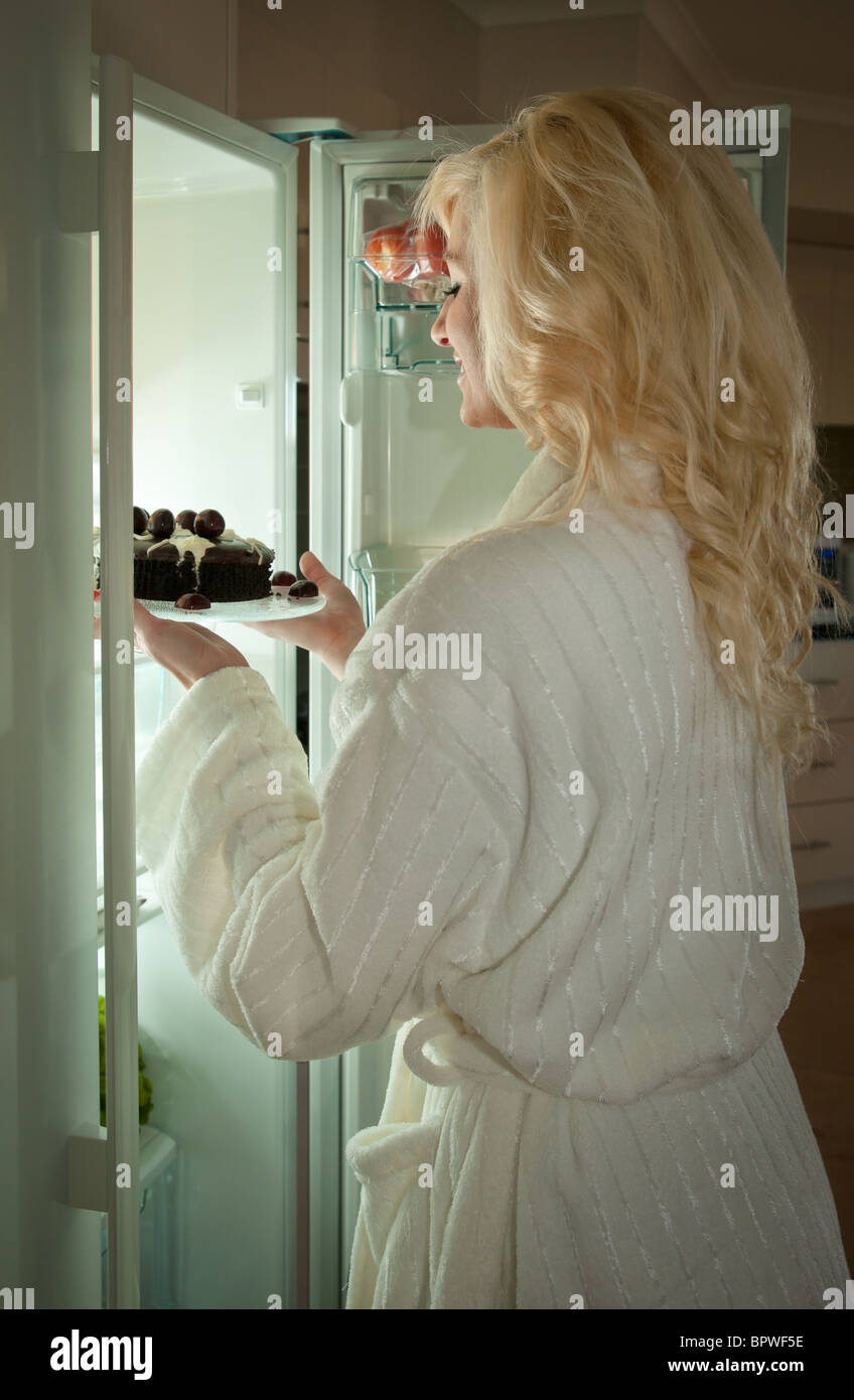 Jeune femme d'obtenir un gâteau de réfrigérateur midnight snack Banque D'Images