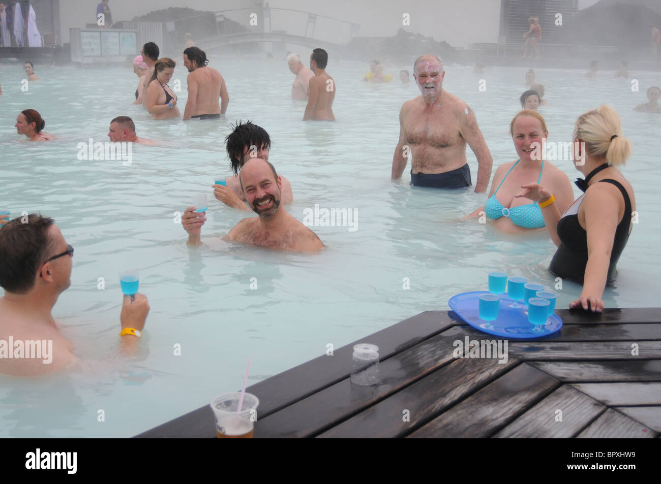 Une serveuse debout dans le Natural spa géothermal Blue Lagoon en Islande sert ses clients avec un verre bleu Banque D'Images