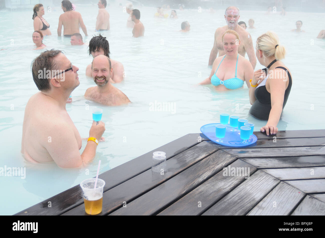 Une serveuse debout dans le Natural spa géothermal Blue Lagoon en Islande sert ses clients avec un verre bleu Banque D'Images