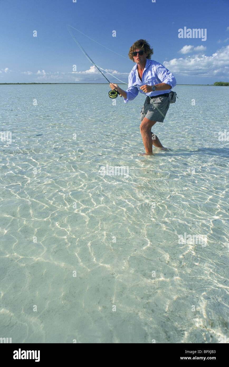 Un pêcheur à mouche d'jette à un poisson dans l'eau peu profonde. Banque D'Images