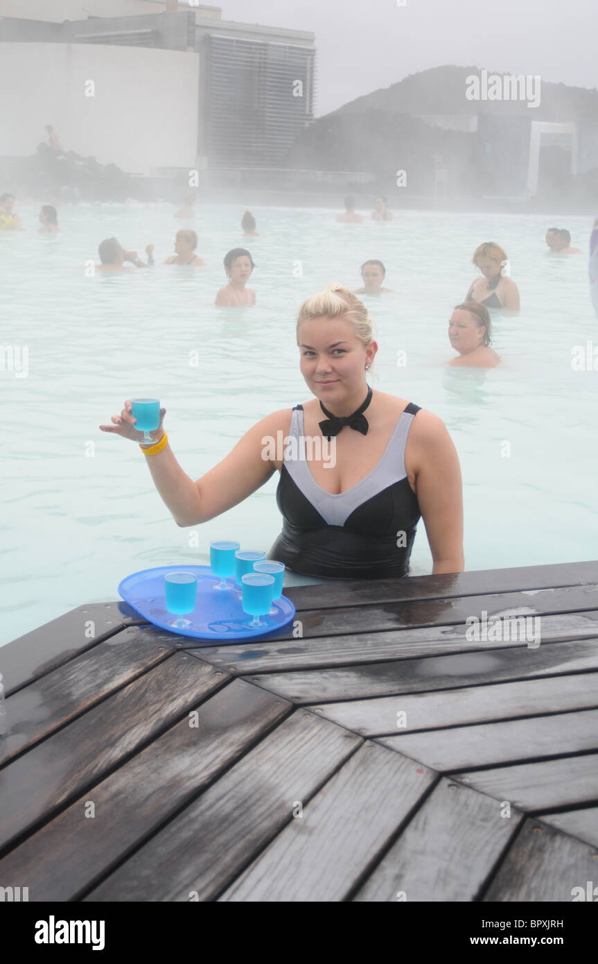 Une serveuse debout dans le Natural spa géothermal Blue Lagoon en Islande pose avec un verre bleu Banque D'Images