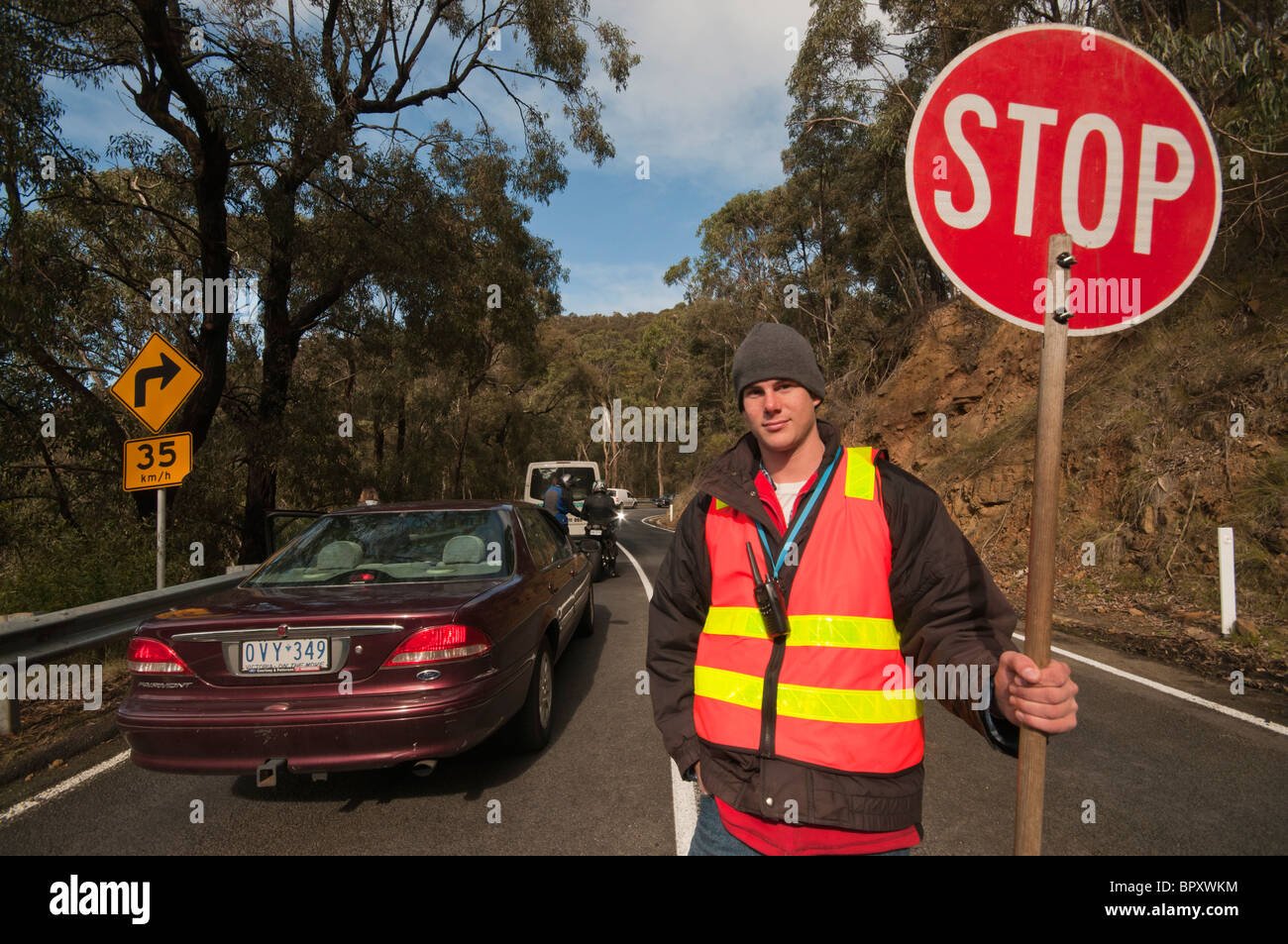 Un travailleur de la route avec un panneau d'arrêt sur la Great Ocean Road, près de Lorne à Victoria en Australie Banque D'Images