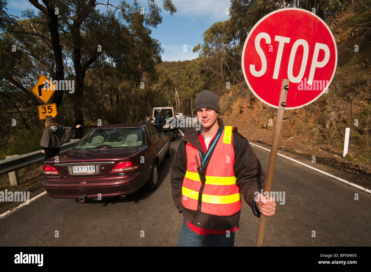 Un travailleur de la route avec un panneau d'arrêt sur la Great Ocean Road, près de Lorne à Victoria en Australie Banque D'Images