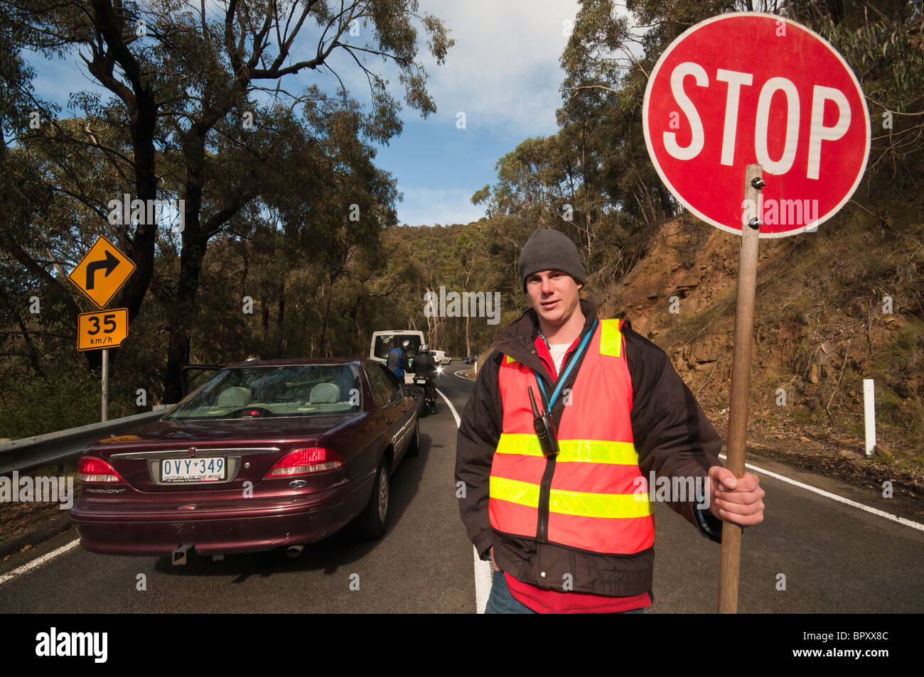 Un travailleur de la route avec un panneau d'arrêt sur la Great Ocean Road, près de Lorne à Victoria en Australie Banque D'Images